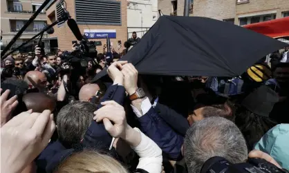  ?? Photograph: Benoît Tessier/AP ?? Bodyguards protect Emmanuel Macron with an umbrella after tomatoes were thrown at him during his Cergy visit.