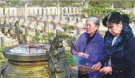  ?? AFP ?? Nguyen Thi Hoa (left) and Hoang Thi No, who were members of the Perfume River squad — a top secret female combat unit formed in 1967, place incense sticks at an official cemetery where the graves of four comrades are located.