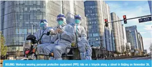  ?? - AFP ?? BEIJING: Workers wearing personal protective equipment (PPE) ride on a tricycle along a street in Beijing on November 26, 2022.