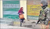  ?? HT FILE ?? A woman crosses barbed wire as a paramilita­ry soldier stands guard in Srinagar on Feb 11.