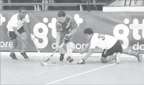  ??  ?? Jason DeSantos (center) of the National Green hockey team, skips past the challenges from the Bounty GCC duo of Mark Sargeant (left) and Samuel Woodroffe during their men’s first division clash in the GTT National Indoor Championsh­ips Thursday at the...