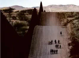  ?? SALWAN GEORGES/WASHINGTON POST/FILE ?? Migrants walked along the border wall on the Arizona side.