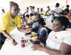  ??  ?? Food For The Poor volunteer Keisha Walker (left) serves Sharon Taylor a meal.