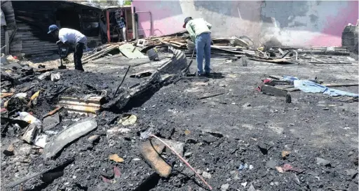  ?? PICTURE: CINDY WAXA ?? COMBING THROUGH THE RUINS: Eight shacks were destroyed by a fire at Masiphumel­ele yesterday morning.