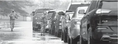  ?? PAUL W. GILLESPIE/CAPITAL GAZETTE ?? National Guard members direct traffic at the testing center in the Vehicle Emission Inspection Program station in Glen Burnie.