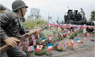  ?? VIRGINIA MAYO THE ASSOCIATED PRESS ?? A mannequin is posed among French, British, Canadian and American flags at the site of the original Pegasus Bridge in Bénouville, Normandy, France, on Friday.