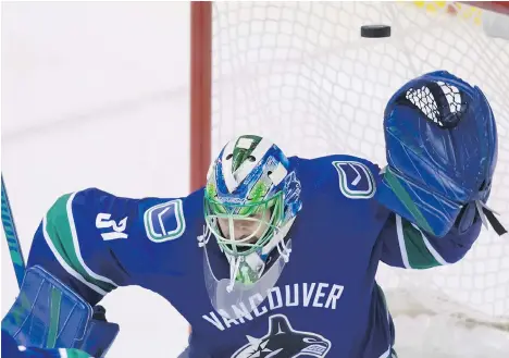  ?? DARRYL DYCK/THE CANADIAN PRESS ?? The puck sails over the head of Vancouver Canucks goalie Anders Nilsson, but stays out of the net during Thursday’s pre-season game against the Calgary Flames. Captain Henrik Sedin says the team’s attack during that win is indicative of what lies ahead.