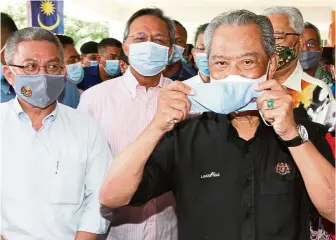  ??  ?? Taking extra
precaution: Muhyiddin holding a face mask after launching the Embracing New Norms campaign at Kompleks Sukan Pagoh in Johor. With him are (from left) Health Minister Datuk Seri Dr Adham Baba, Johor Mentri Besar Datuk Hasni Mohammad, (partially hidden) Communicat­ions and Multimedia Minister Datuk Saifuddin Abdullah and Senior Minister Datuk Seri Ismail Sabri Yaakob.