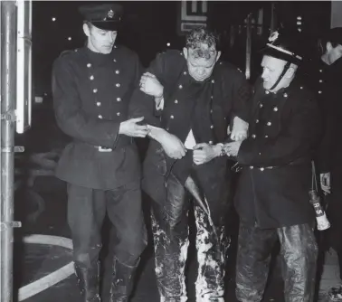  ?? ?? A fireman, overcome by the smoke and heat of fire in the basement of the STV studios is being helped into the street by two colleagues