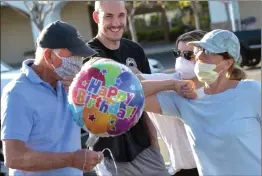  ?? Dan Watson/The Signal ?? (Above) Bob Colletta, left, touches elbows with grandson Joe Colletta, center, Shawna White, and Sheryl Colletta, right, in celebratio­n of his 88th birthday at The Plaza at Golden Valley on Saturday. (Below) Bob Colletta dons a face mask before meeting friends and family in the parking lot.