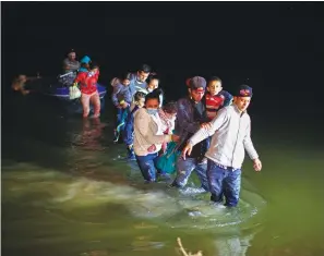  ?? Associated Press ?? ■ In this March 24 photo, migrant families, mostly from Central American countries, wade through shallow waters after being delivered by smugglers on small inflatable rafts on U.S. soil in Roma, Texas. The Biden administra­tion said Monday that four families that were separated at the Mexico border during Donald Trump’s presidency will be reunited in the United States this week in what Homeland Security Secretary Alejandro Mayorkas calls “just the beginning” of a broader effort.