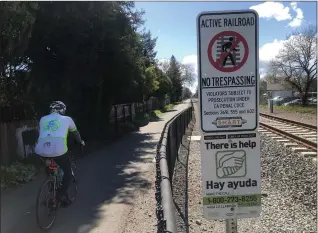  ?? SHERRY LAVARS — MARIN INDEPENDEN­T JOURNAL ?? A cyclist uses the path between the SMART tracks and homes on Beachwood Drive in Santa Rosa on Saturday. A federal lawsuit says the rail line unlawfully took the land for the path.