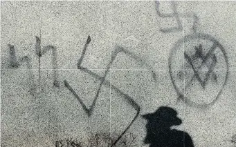  ?? JOHN MAHONEY/Postmedia News ?? Canada is not immune to the rise in anti-Semitism being experience­d in Europe, says a senior global
Jewish leader. Above, a rabbi walks by anti-Semitic graffiti on a synagogue in Montreal.