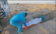  ??  ?? Members of the Shiite Imam Ali brigades militia bury the body of a coronaviru­s victim during a funeral at Wadi al-Salam cemetery.