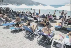  ??  ?? Tourists soak up the sun as Greece’s future hangs in balance