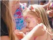  ??  ?? Cora Toth, 3, gets her face painted by her mother, Corrie, of Catasauqua.