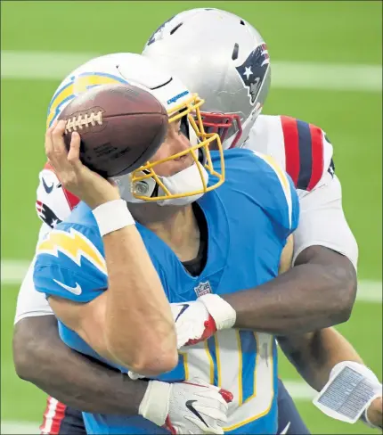  ?? GETTY IMAGES ?? Patriots defensive tackle Adam Butler hits Chargers quarterbac­k Justin Herbert and forces him to throw an incomplete pass during the second quarter Sunday afternoon.