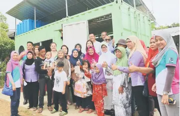  ??  ?? Fatimah (front, fifth right) and Ting (standing left at door) and others pose in front of the container home. Also seen is Sarawak Islamic Education Service Bureau director Datu Dr Adi Badiozaman Tuah (standing right at door).