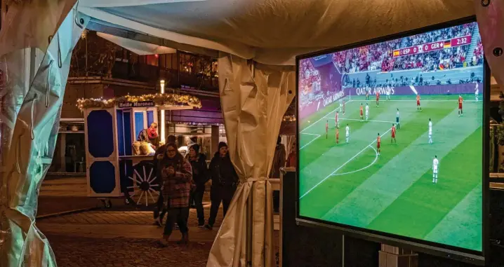  ?? Fotos: Matthias Rietschel, dpa/florian Eisele ?? Leere Hütte: In Dresden interessie­rt der Weihnachts­markt die Menschen sehr viel mehr als das Wm-vorrundens­piel gegen Spanien. Einsam sendet der Fernseher ins Nichts.