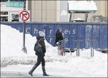  ?? BILL SIKES / ASSOCIATED PRESS ?? Pedestrian­s walk past a snow-clearing operation Friday in Boston after the previous day’s snowstorm.