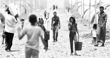  ??  ?? Displaced Iraqis, who had fled the violence around the northern Iraqi city of Mosul as a result of a planned operation to retake the Iraqi city from jihadists, walk at the Jadaah camp on the outskirts of Al-Qayyarah, south of Mosul. — AFP photo