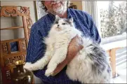  ?? SPERANZA/THE NEW YORK TIMES STEPHEN ?? John Owen, who has fostered more than 150 cats over the past decade, holds his own cat, Vita, who put on weight during the pandemic, in Boulder, Colorado, on Feb. 13. Many owners have been caught off guard as their dogs and cats gained weight during the pandemic.