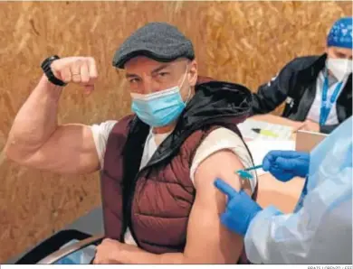  ?? BRAIS LORENZO / EFE ?? Un hombre bromea mientras le inyectan ayer la vacuna de AstraZenec­a en Orense.