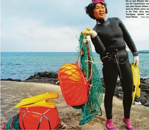  ?? Fotos: dpa ?? Bis zu zwei Minuten kön nen die Taucherinn­en von Jeju unter Wasser bleiben. Auch im Winter gehen sie in die Tiefe. Nach dem Tauchgang spendet ein Feuer Wärme.