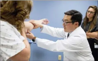  ?? ANDREW HARNIK — THE ASSOCIATED PRESS ?? In this photo, Dr. David Song accompanie­d by nurse Christina Barra, right, examines Susan Wolfe-Tank’s arm for signs of lymphedema during a post-surgery checkup at MedStar Georgetown University Hospital in Washington. Wolfe-Tank underwent lymph node...