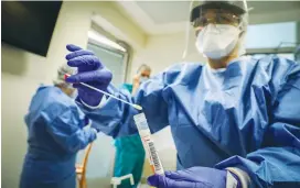  ?? (Yossi Zamir/Flash90) ?? WORKERS IN protective gear handle a coronaviru­s test sample at Hadassah-University Medical Center, in Jerusalem’s Ein Kerem, yesterday.