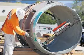  ??  ?? SANTIAGO GOMEZ applies a protective coating on a pipe at the Carlsbad plant, which is touted as the largest desalinati­on project in the Western Hemisphere.