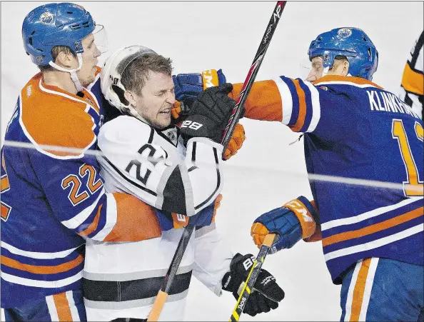  ?? — THE CANADIAN PRESS ?? Trevor Lewis of the Los Angeles Kings is punched by the Oilers’ Rob Klinkhamme­r as Edmonton’s Keith Aulie holds Lewis Tuesday night. With the Oilers’ 4-2 victory in Edmonton over the Kings, Vancouver clinched a playoff berth in the Western Conference.