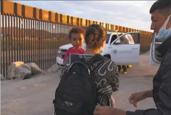  ?? Eugene Garcia / Associated Press ?? A migrant family from Brazil waits to be processed by U.S. Border Patrol agents last month after they passed through a gap in the border wall from Mexico into Yuma, Ariz.