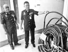  ??  ?? Ladamah (right) showing the TM cables that were seized from the suspects.