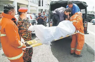  ??  ?? One of the bodies being moved into a police vehicle to be brought to the Sarawak General Hospital (SGH) for post-mortem.