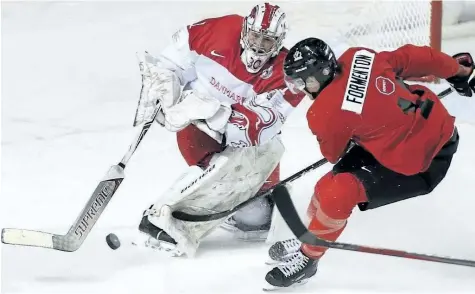  ?? PETER POWER/ THE CANADIAN PRESS ?? Team Denmark goaltender Emil Gransoe shoots the puck away from Team Canada’s Alex Formenton during a world junior exhibition game in St Catharines on Friday.