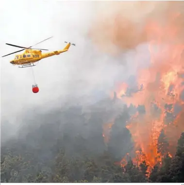  ?? EP ?? Un helicópter­o descarga ayer agua sobre las llamas de un incendio forestal en Tenerife Norte.