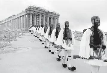  ?? PETROS GIANNAKOUR­IS/AP ?? Greek Independen­ce Day: Members of the Presidenti­al Guard march from the Parthenon after a flag-raising ceremony Thursday in Athens. Greece’s celebratio­ns for the 200th anniversar­y of its war of independen­ce culminated in a military parade attended by dignitarie­s from Britain, France and Russia but no members of the public.