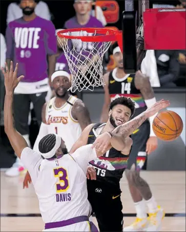  ?? Mike Ehrmann Getty Images ?? DENVER’S JAMAL MURRAY gets tangled up with Anthony Davis as they battle for a loose ball during the third quarter. Davis scored 27 points, but Murray made big plays down the stretch for the Nuggets.