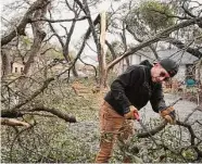  ?? Jay Janner/Associated Press ?? Jojo Mairena-Davila removes a tree from his yard in Austin, where dense tree canopy made downed power lines widespread.
