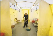  ?? Robert F. Bukaty / Associated Press ?? A nursing director at Central Maine Medical Center mops the floor of a tent outside the emergency entrance to the hospital March 13 where patients are tested for the coronaviru­s in Lewiston, Maine.