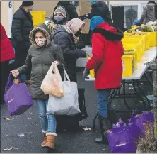  ??  ?? Maria Guzman Salazar (front) carries bags of food after visiting LaMarr-Murphy’s food pantry.