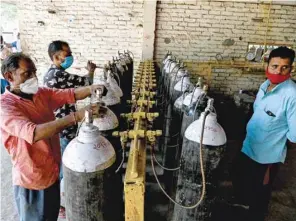  ??  ?? Employees at an oxygen refilling centre in Moradabad, India, refill cylinders for coronaviru­s patients.