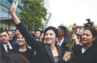  ??  ?? Yingluck waves to supporters as she leaves the Supreme Court in Bangkok yesterday.