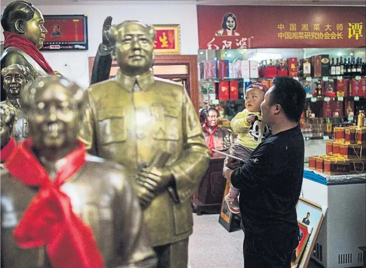  ?? JOHANNES EISELE / AFP ?? Un padre le enseña a su hijo estatuas de Mao en una tienda dedicada a la memoria del dirigente chino en Shaoshan, su localidad natal