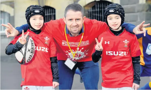  ??  ?? > Shane Williams with twins Sammy, left, and Jamie Jones at Twyn School, Caerphilly, during the ‘Wear Red for Wales and Velindre’ day