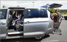  ??  ?? Melanie Matcheson, loading groceries into her Chrysler Pacifica, says no vehicle other than a minivan could efficientl­y haul her family of two adults and five children.