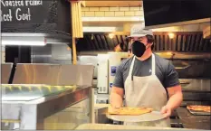  ??  ?? Cal McKinney, an employee at Grigg Street Pizza, puts out fresh slices at the shop in Greenwich on Friday.