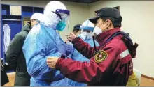  ?? LI JIANING / FOR CHINA DAILY ?? Wang Yang (right), captain of the emergency medical team from The Second Xiangya Hospital of Central South University, helps Yu Song, head of Wuhan’s Wuchang district, put on protective clothing during Yu’s visit to the district’s temporary hospital in Hubei province, on Feb 7.