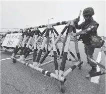  ?? JUNG YEON-JE/AFP/GETTY IMAGES ?? A South Korean soldier sets a barricade on the road leading to North Korea’s Kaesong joint industrial complex on Friday. Both sides are warning of coming military action.